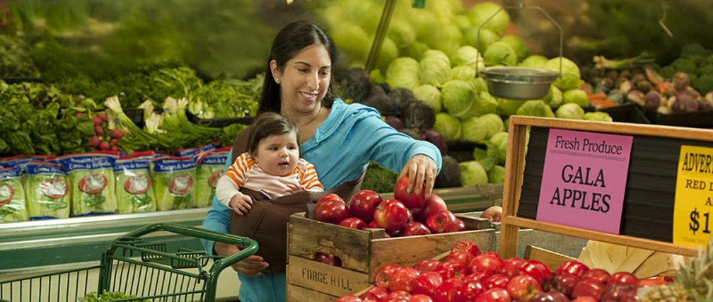 Mother with infant shopping for produce