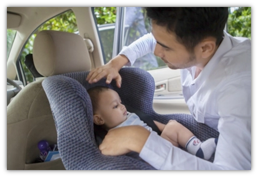 Father strapping child into car seat
