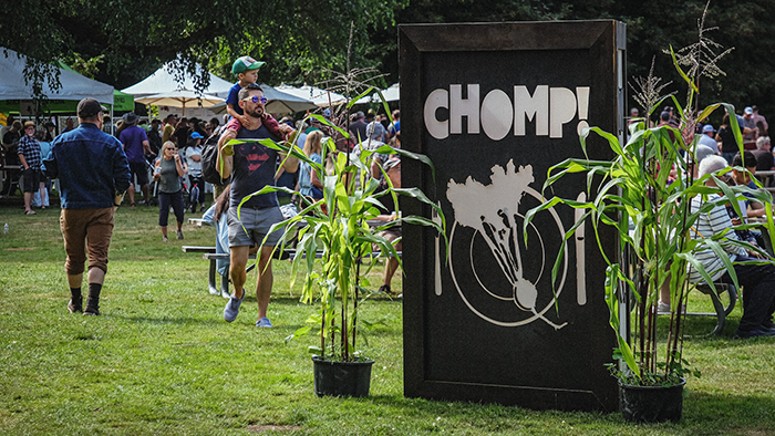 CHOMP summer event with people, a sign and corn stalks