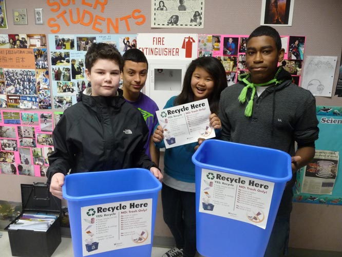 Students at McKnight Middle School attach signs to recycling bins