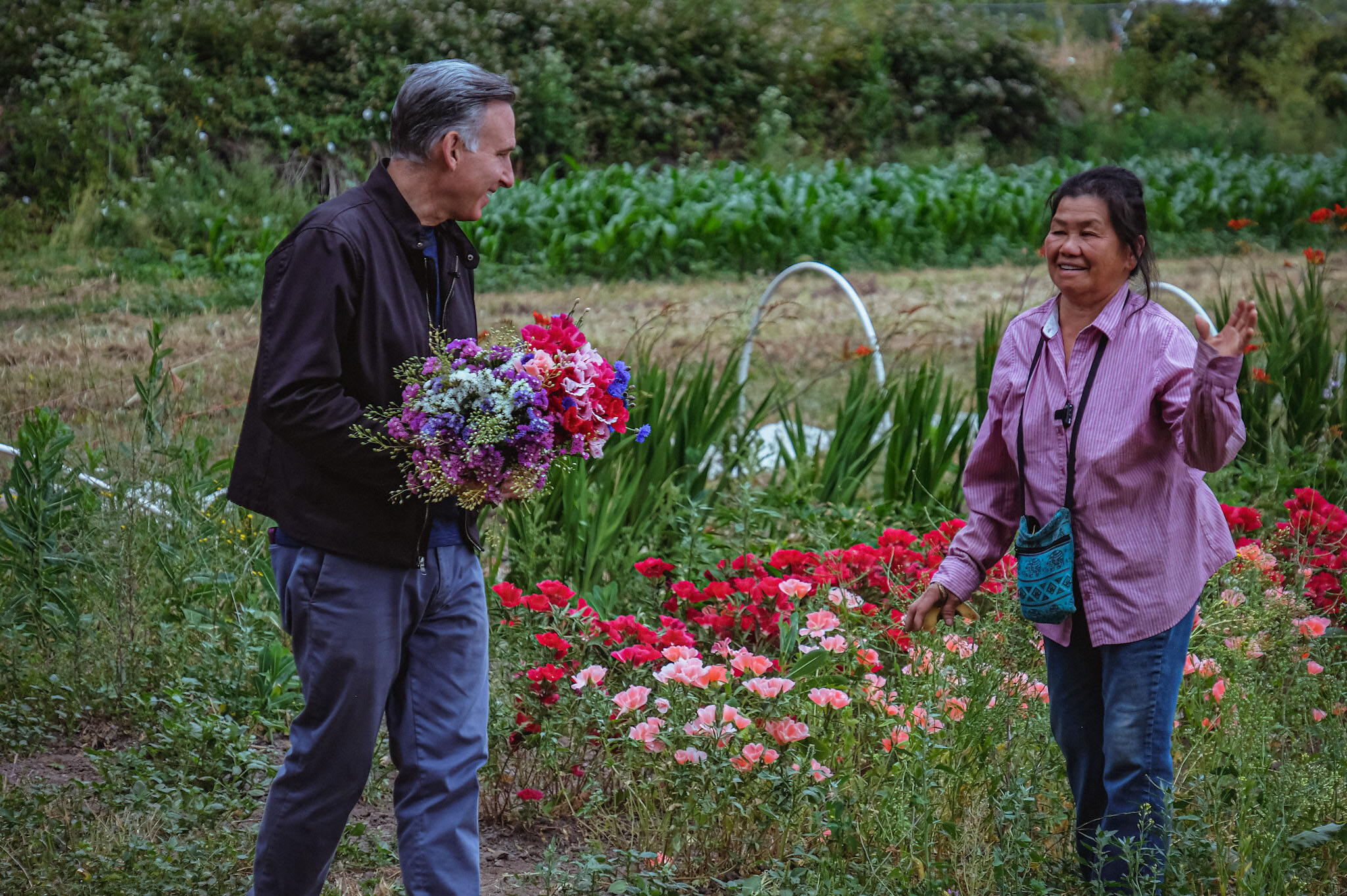Dow Constantine holding flowers while talking with a farmer.