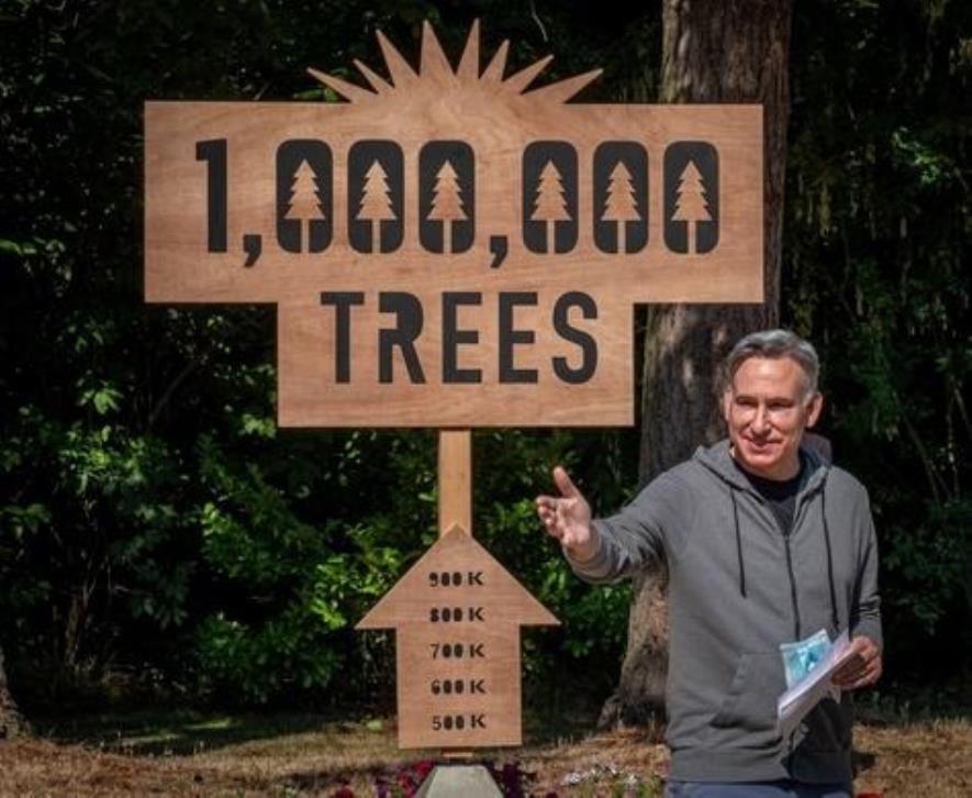 A photo of King County Executive Dow Constantine in front of a 1,000,000 Trees sign.
