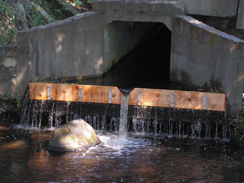 Photograph of culvert with wooden board installed at lip of culvert