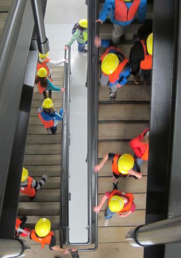 Youth with yellow hard hats walking down the stairs at a treatment plant