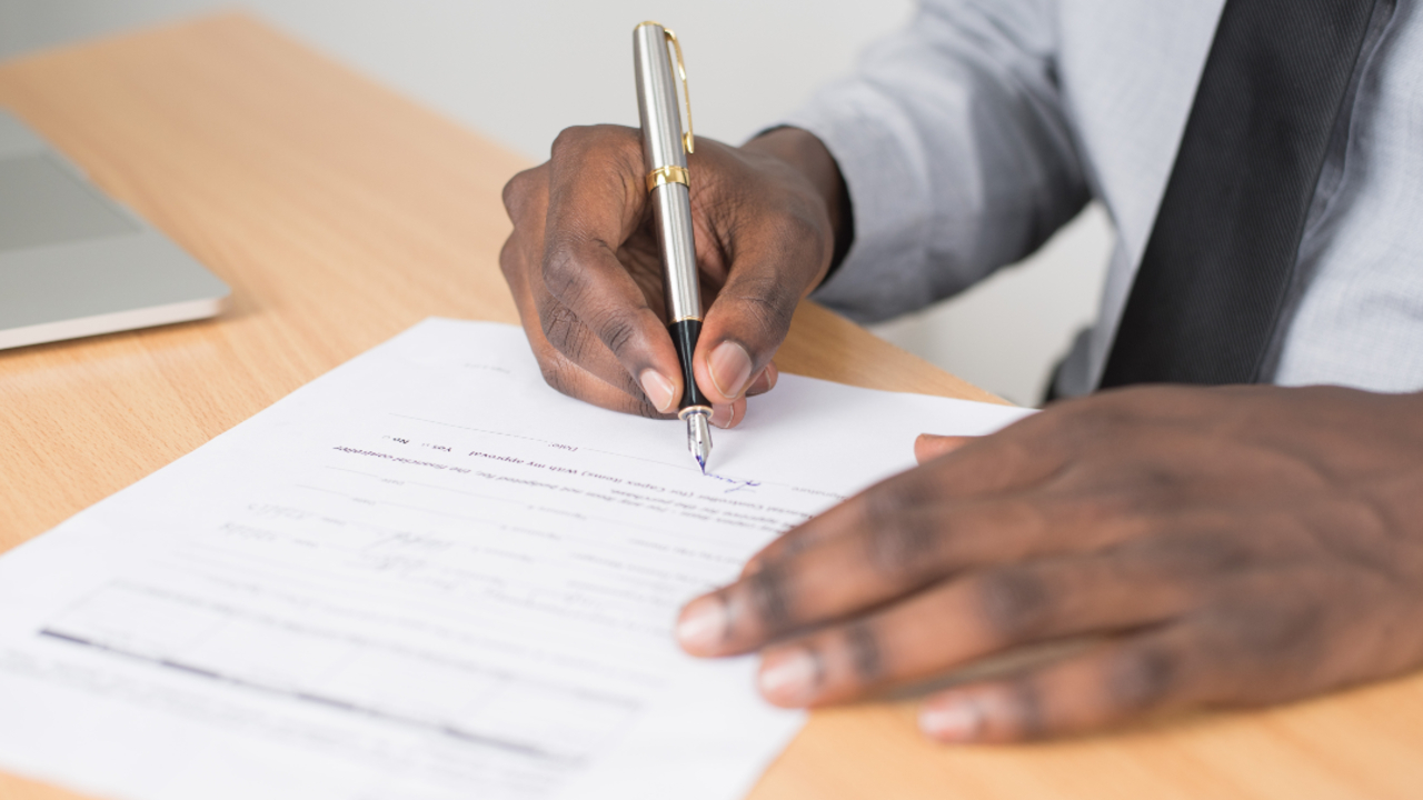 Closeup of a person holding a pen and signing a contract