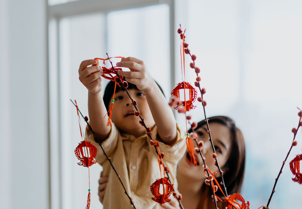 Green Lunar New Year header - image of a child hanging decorations