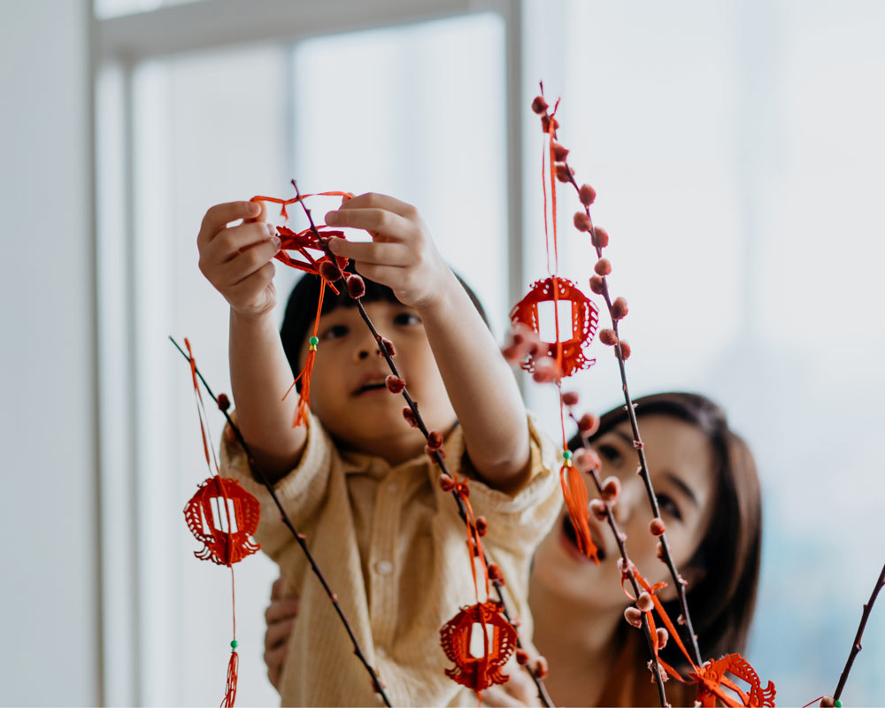 image of a child hanging decorations - link to Green Lunar New Year