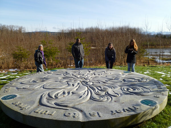Four people standing at the edge of a large round artwork located in the Chinook Bend Natural Area
