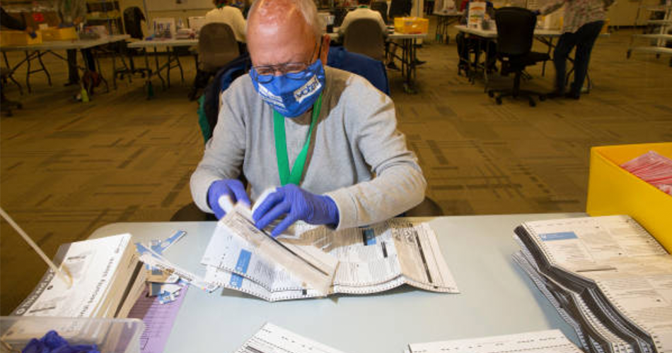 Election worker opening ballots while wearing mask
