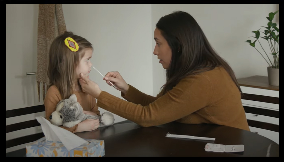Woman performing nasal swab on child