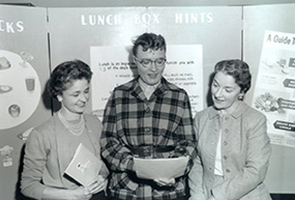 Three women standing together and reading from a paper