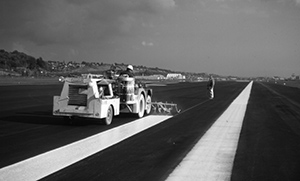 Workers striping an airfield runway
