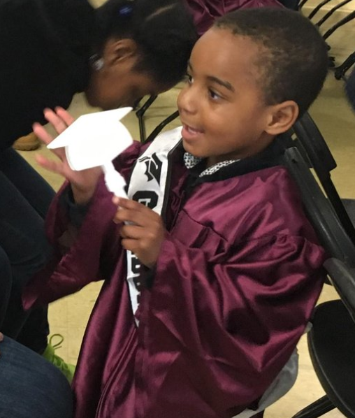 A young boy wearing a graduation gown.