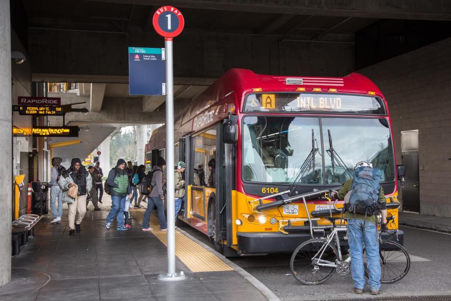 A cyclist putting their bike on the front of a King County Metro bus.